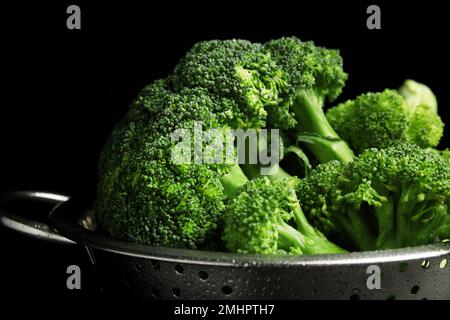 Brocoli vert frais en passoire sur fond noir, gros plan Banque D'Images