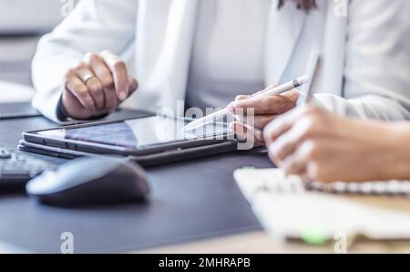Les mains de deux collègues féminins utilisent une tablette numérique et un ordinateur portable. Une réunion d'affaires pour discuter de la gestion financière, de la comptabilité ou de la gestion financière Banque D'Images