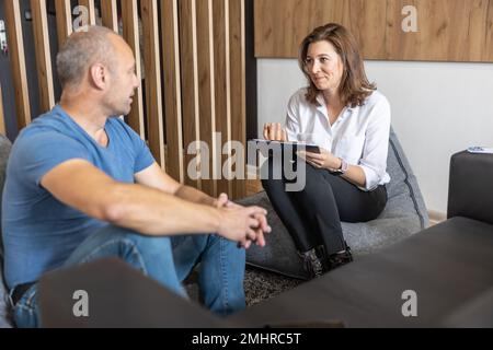 Une femme d'affaires souriante lors d'une interview avec un homme qui a fait ses cinquante ans de carrière. Banque D'Images