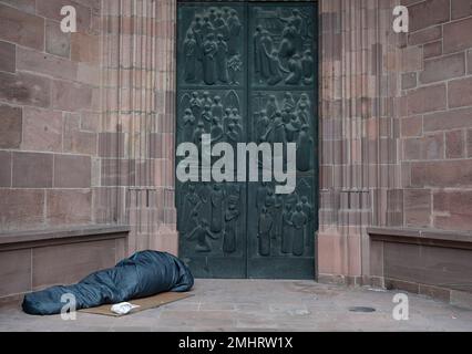 27 janvier 2023, Hesse, Francfort-sur-le-main: Un sans-abri dort dans son sac de couchage devant un portail latéral de la cathédrale de Francfort. En particulier pendant la saison froide, les sans-abri dépendent des offres d'aide. Photo : Boris Roessler/dpa Banque D'Images