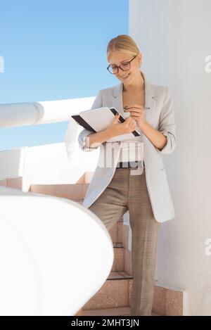 Jeune femme d'affaires blonde prenant des notes en se tenant debout Banque D'Images