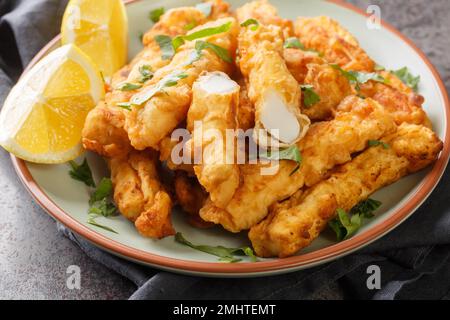 Des lamelles chaudes panées de calamars sont servies avec des quartiers de citron sur l'assiette de la table. Horizontale Banque D'Images