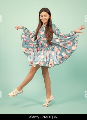 Pleine longueur surjoyée adolescent fille 12 13 14 ans saut vieux isolé sur fond bleu studio. Un saut amusant. Enfant en robe de mouvement d'été. Banque D'Images