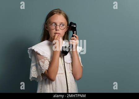 Appel étrange. Portrait d'une fille à l'écoute du téléphone. Style rétro. Banque D'Images