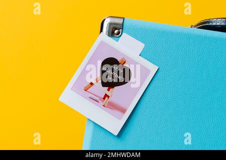 gros plan d'une photo aninstant, montrant un tableau noir en forme de coeur avec le texte happy valentin jour écrit, attaché à une letherette su rétro bleu Banque D'Images