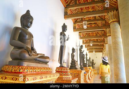 Visiteur impressionné par une rangée d'images de Bouddha antique enchâssées au Cloître du Temple de marbre à Bangkok, Thaïlande Banque D'Images