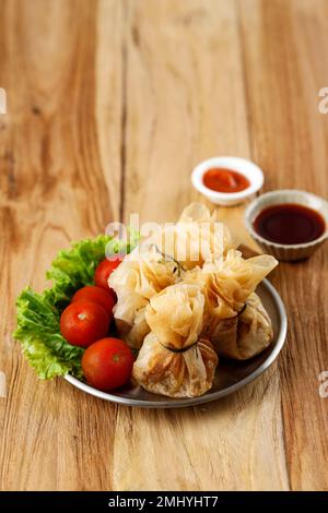 Wonton, des merveilles orientales frites fourrées de crevettes et d'oignons de printemps, servi avec des sauces soja et Chili. Banque D'Images
