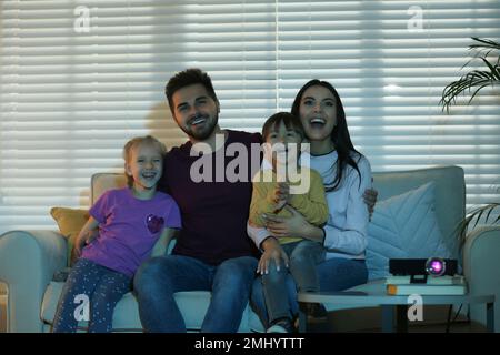 Une famille ravie de regarder des films à l'aide d'un vidéoprojecteur à la maison Banque D'Images