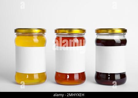 Différents types de miel avec des étiquettes vierges isolées sur blanc Banque D'Images