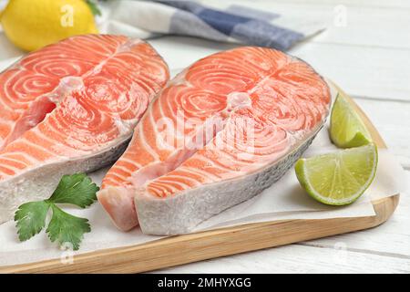 Saumon frais cru avec persil et citron vert sur table blanche en bois. Délicatesse du poisson Banque D'Images