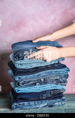 Femme pliage élégant Jean sur table en bois, gros plan Banque D'Images