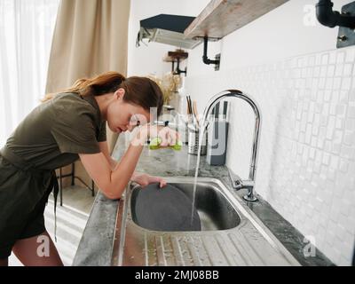 Femme fatiguée et irritée mains sans gants lave la vaisselle avec une éponge de lavage de vaisselle, des tâches ménagères, pas de lave-vaisselle, consommation d'eau élevée. Élégant Banque D'Images