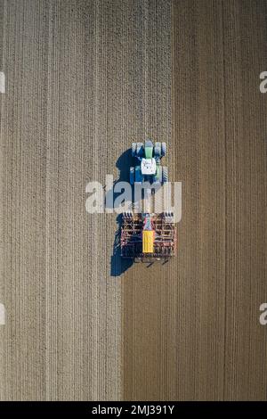 Vue aérienne sur le tracteur avec semoir pneumatique, machine agricole pour semis, travail dans un champ au printemps Banque D'Images