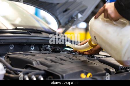 Professionnel de service de voiture homme changeant l'huile moteur par le moteur de voiture, concept de service de voiture Banque D'Images