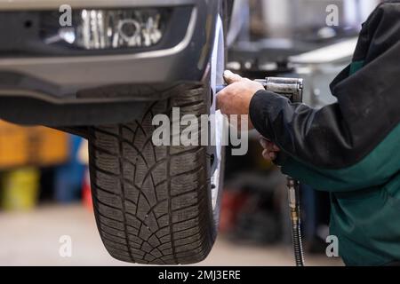 Voiture, mécanicien automobile, changement de pneus, roues sur la voiture par clé pneumatique, centre d'entretien Banque D'Images