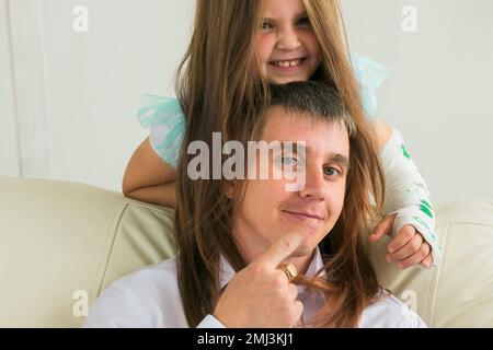 Père et sa fille s'amusent dans leur salon. Petite fille ont la main blessée mais elle est heureuse être ensemble son père Banque D'Images