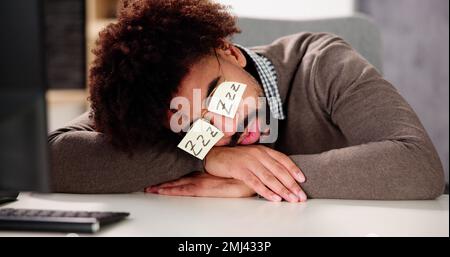 Homme afro-américain fatigué dormant au bureau Banque D'Images