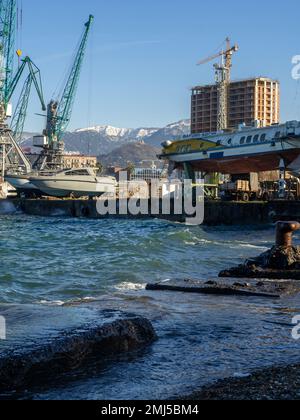 Batumi, Géorgie. 01.11.2023 navires et grues dans le port de chargement. Vieux bollard rouillé sur la mer. Batumi. La mer domine la jetée. Anciennes dalles de béton Banque D'Images