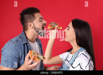 Un jeune couple heureux avec une pizza sur fond rouge Banque D'Images