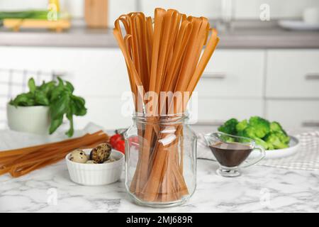 Nouilles de sarrasin non cuites et ingrédients frais sur une table en marbre blanc dans la cuisine Banque D'Images
