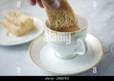 verser des biscuits sucrés dans une tasse de café sur une table en bois Banque D'Images