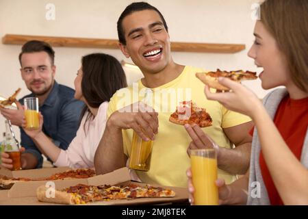 Groupe d'amis qui ont la fête avec une délicieuse pizza dans le café Banque D'Images