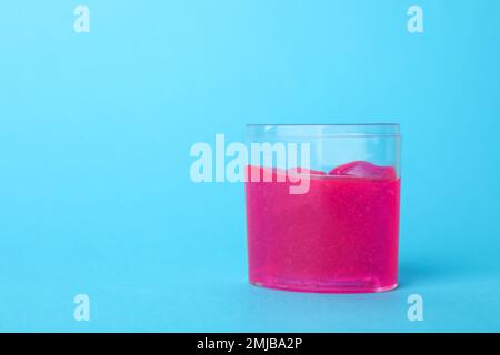 Chaux rose dans un récipient en plastique sur fond bleu clair. Espace pour le texte Banque D'Images