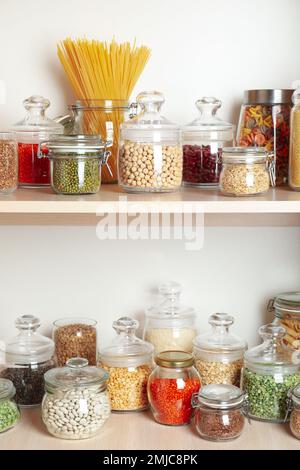 Bocaux en verre avec différents types de gruaux et de pâtes sur des étagères en bois Banque D'Images