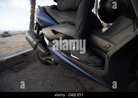 Gros plan sur les chaussures de protection d'un motard à bord de son scooter Banque D'Images