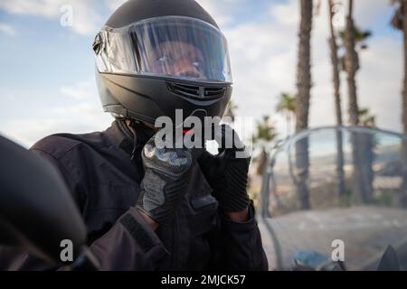 Un motard africain porte un casque tout en étant assis sur sa moto, sécurité routière Banque D'Images