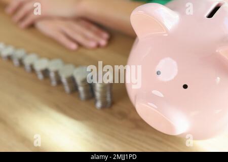 De nombreuses piles de pièces de différentes hauteurs et de pigey banque sur table en bois. Banque D'Images