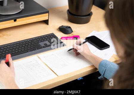 Esquisse de l'élément filaire pour le site Web. Femme designer travaillant sur une application mobile, dessin sur papier. Banque D'Images