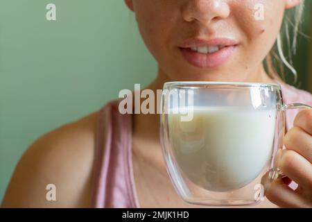 Une jeune fille ukrainienne tient une tasse en verre transparent avec du lait le matin Banque D'Images