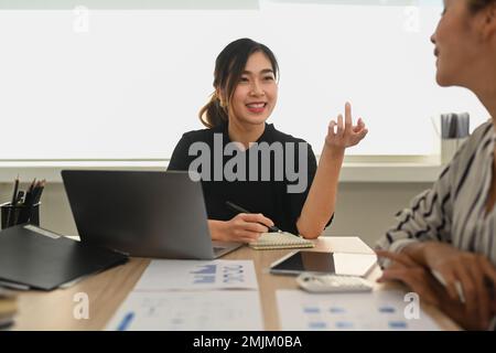 Femme asiatique confiante responsable expliquant les nouvelles stratégies à ses collègues lors d'une réunion au bureau Banque D'Images
