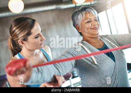 Avec l'exercice, les années d'or continuent à s'améliorer. une femme âgée utilisant des bandes de résistance avec l'aide d'un physiothérapeute. Banque D'Images