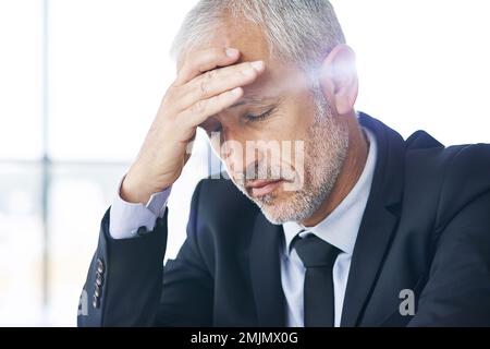 HES est confronté à un défi difficile. un homme d'affaires mature qui cherche à mettre l'accent sur le travail. Banque D'Images