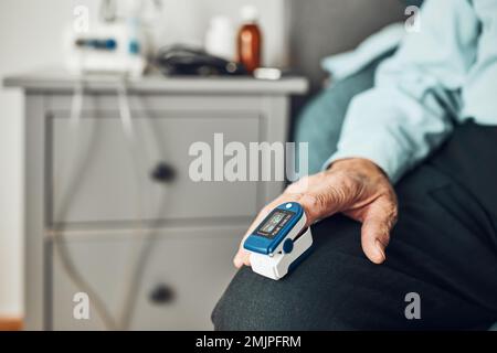 Homme âgé mesurant le degré de saturation en oxygène du sang et de la fréquence cardiaque à la maison à l'aide d'un oxymètre de pouls. Traitement à domicile du virus. Vérification de la santé Banque D'Images