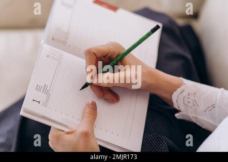 la main de la femme écrit sur un livre en spirale sur la table. les mains de la fille écrivent dans le journal Banque D'Images