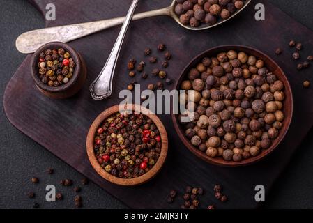 Spice couleur brun d'allépice non meulée dans une soucoupe en bois sur un fond en béton foncé Banque D'Images