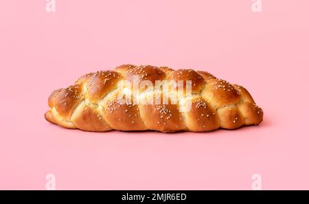 Pain de challah frais minimaliste sur une table rose. Délicieux pain tressé isolé sur un fond coloré. Banque D'Images