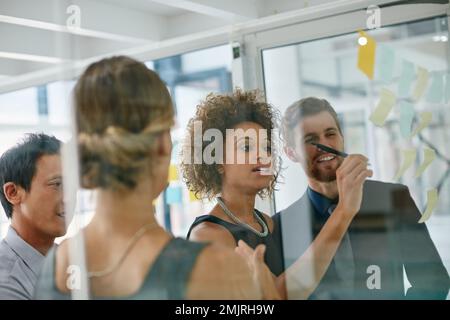 Couvrant toutes les bases. les collègues utilisent des notes adhésives contre le mur pendant une séance de brainstorming. Banque D'Images