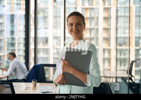 Femme entrepreneure accomplie souriant fièrement à son lieu de travail Banque D'Images