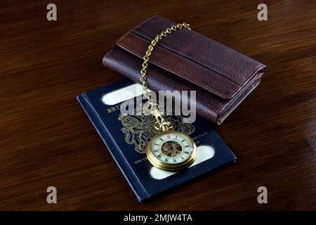 Ancienne montre de poche avec portefeuille en cuir et passeport britannique vintage sur une table en bois Banque D'Images