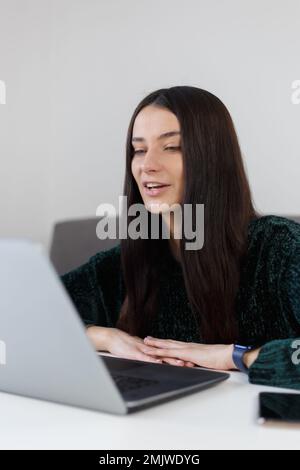 Un jeune entrepreneur parle sur une webcam pendant un appel vidéo. Femme blanche à la fin de 20s parlant sur ordinateur portable web CAM à la maison Banque D'Images
