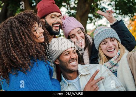 Gros plan d'un groupe de jeunes visages, souriant et s'amusant ensemble. Des amis multiraciaux heureux avec des chapeaux, des manteaux et des vêtements d'automne appréciant un jour de week-end. Concept de style de vie. Photo de haute qualité Banque D'Images