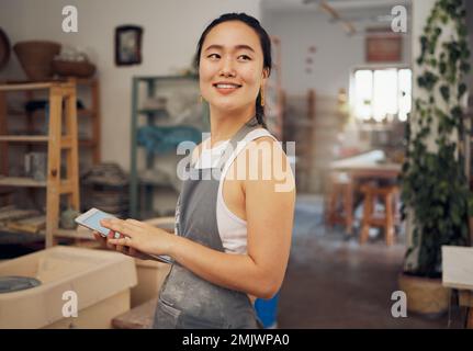 Tablette, petite entreprise et femme en atelier de poterie pour la mise en route de la céramique, la recherche et le site Web en ligne. Art créatif, ecommerce et femme asiatique avec Banque D'Images