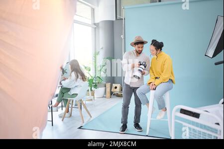 Photographie, appareil photo et photographe parlant à un modèle pour choisir une image de la séance photo dans le studio. Créatif, art et caméraman choisissant le Banque D'Images