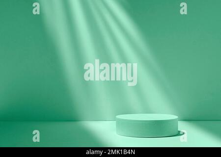 Podium cylindre dans un faisceau de lumière sur un fond vert avec des ombres et de la lumière pour montrer le produit. Photo de haute qualité Banque D'Images