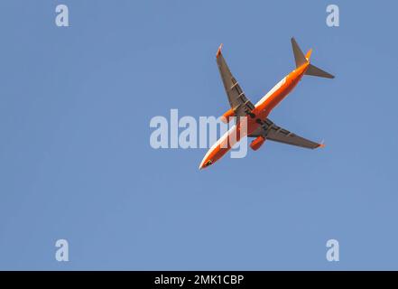 avion passager rouge en gros plan volant dans le ciel Banque D'Images