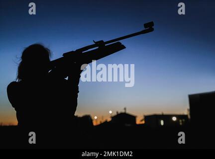 silhouette de fille la nuit sur fond de maisons visez un fusil Banque D'Images